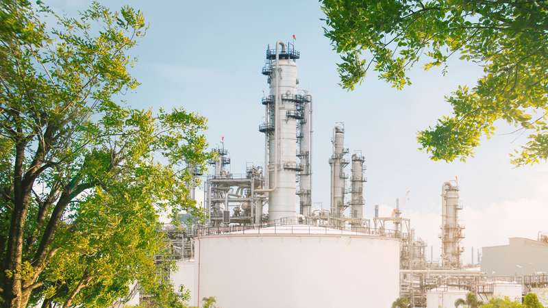 CO2 produzierende Industrieanlage mit grünen Pflanzen im Vordergrund, was die grüne Zukunft von CCUS beschreiben soll
