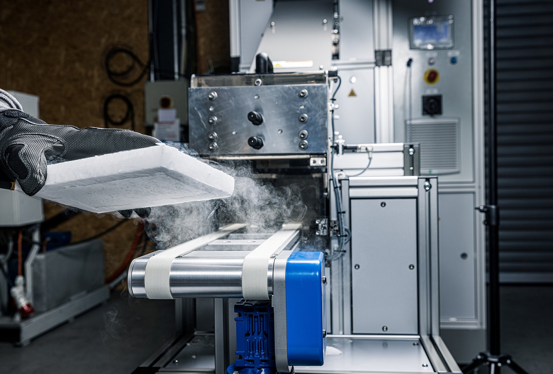 An insulated dry ice block is being removed from the conveyor of a BP425i ice loader by an operator.