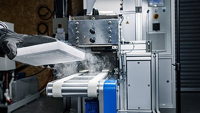 An insulated dry ice block is being removed from the conveyor of a BP425i ice loader by an operator.